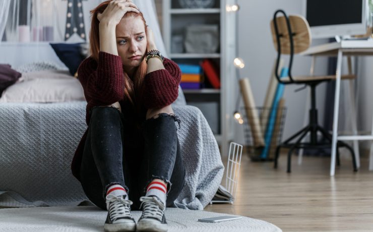 Worried girl sitting on the floor holding her head