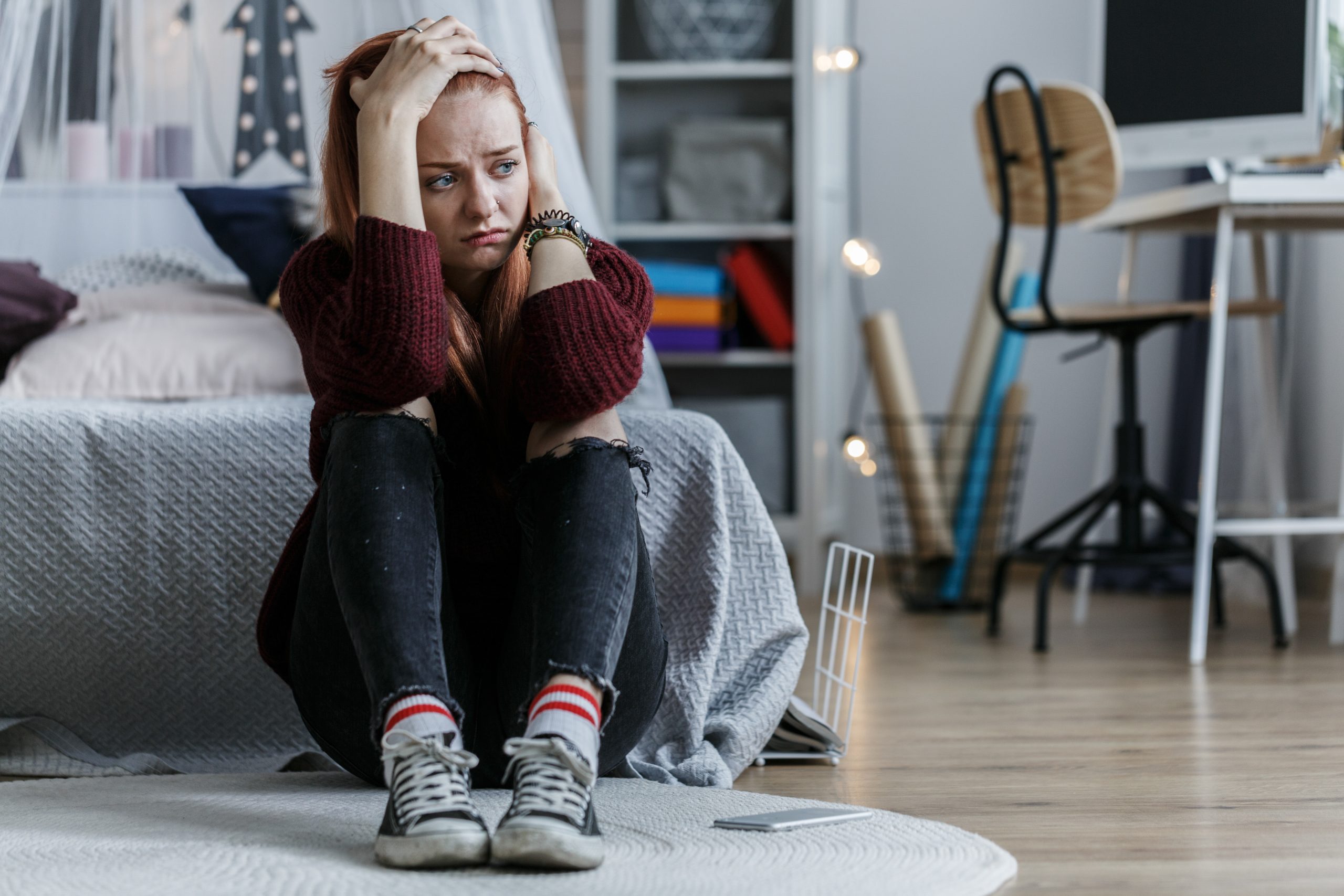 Worried girl sitting on the floor holding her head